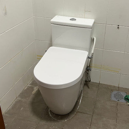 White toilet in a bathroom with tiled walls and floor.